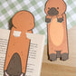 Two brown and tan platypus bookmark cutouts. The platypus are standing on a book. The platypus are facing forward, The platypus are holding their front paws in front of them.